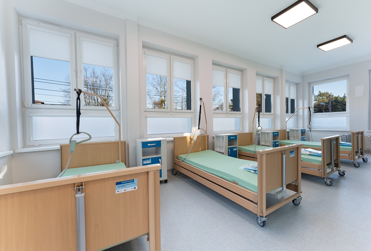 Sala z czterema łóżkami rehabilitacyjnymi z regulacją i szafkami przyłóżkowymi